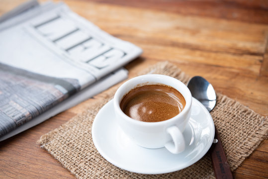 cup of coffee espresso and newspaper on wood table.