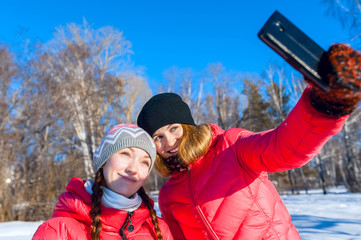 Two young happy smiling girl photographed on the background of blue sky in winter park. Outdoor portrait.