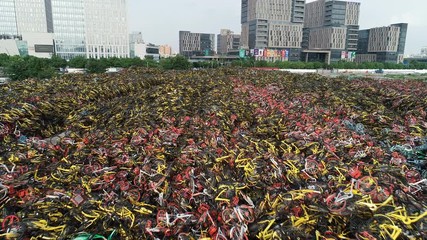 Drone flight over massive piles of disposed rental bicycles in an abandoned parking lot in Shanghai, overcapacity problem in China