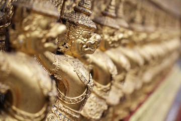 group of golden Garuda statue stand around , the bronze symbol of Thai government, giant ancient gold eagle with crown sculpture antique signature on temple royal palace wall