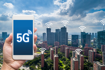 hand holding mobile smart phone with cityscape,5G network interface and wifi icon concept