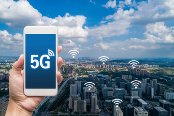 hand holding mobile smart phone with cityscape,5G network interface and wifi icon concept