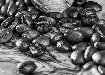 Roasted coffee beans on the desk made from olive tree with contrast picture on the surface in morning sun rays and with shadows