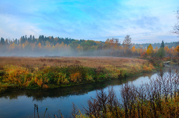 Fototapeta na wymiar Foggy autumn landscape with small forest river.