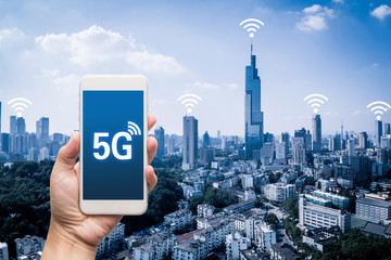 hand holding mobile smart phone with cityscape,5G network interface and wifi icon concept