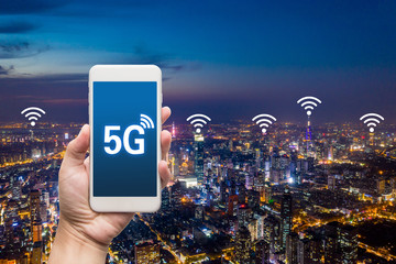 hand holding mobile smart phone with cityscape,5G network interface and wifi icon concept