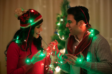 young couple wrapped fairy light at Christmas Celebrations