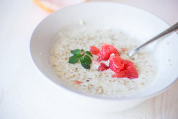 sweet oatmeal with slices of red grapefruit in a ceramic bowl