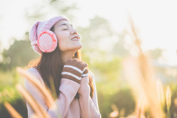 Portrait of young woman wore a knitted sweater and gloves, and the earmuff in fresh morning relax in the winter.