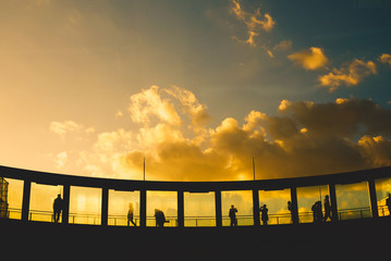 Silhouette of a group of people standing watching the sunset on the roof of a tall building.
