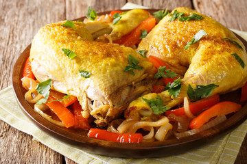 Spicy chicken legs cooked with saffron and fried peppers with onions close-up on a plate. horizontal