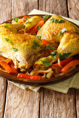 Delicious chicken legs stewed with saffron and vegetables close-up on a plate. vertical