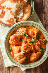 Indian Karhai chicken in a spicy sauce close-up served with naan bread. Vertical top view