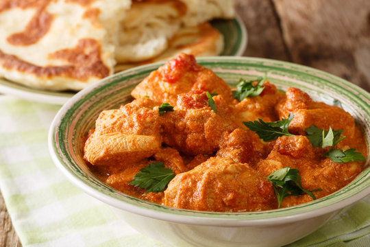 Indian food spicy karhai chicken in tomato sauce close up and naan on the table. horizontal
