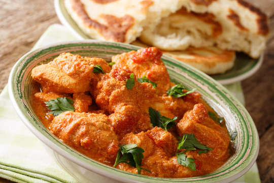 Traditional Indian spicy karhai chicken close-up and fresh naan bread on the table. horizontal, rustic