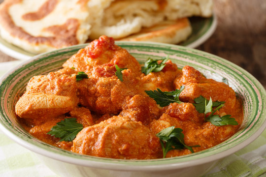 Delicious hot Indian Karhai chicken in a spicy sauce close-up served with fresh naan bread. horizontal