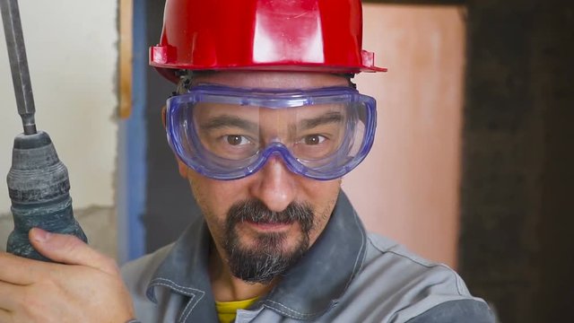 portrait of an adult man in a helmet on his head and with a perforator in his hand