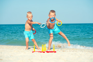 Brothers playing a game throwing rings on the beach.