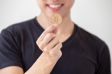 Young asian man hold golden bitcoin coins in hand. Virtual currency. Crypto currency. New virtual money.