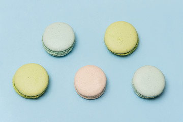 Colorful macarons or macaroons on blue paper background top view. Minimalistic flat lay composition