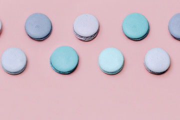 Fototapeta premium Colorful macarons or macaroons on pink paper background top view. Minimalistic flat lay composition