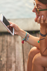 Girl using cellphone while lying on a swimming pool deck lounge bed.