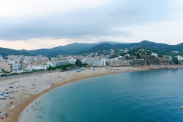 Tossa de Mar, Catalonia, Spain, August 6, 2018. View of the bay, sandy beach with people at sunset.