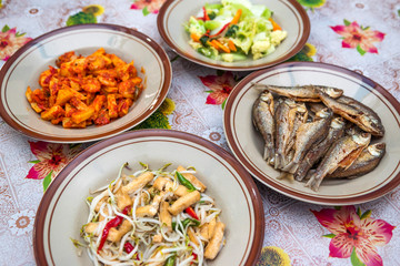 Assorted Indonesian home made food served on plates : kentang balado, sayur cap cay, ikan goreng, tumis toge tahu