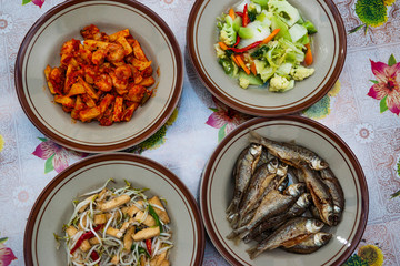 Assorted Indonesian home made food served on plates : kentang balado, sayur cap cay, ikan goreng, tumis toge tahu