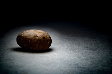 Rough pebble stones on the background of dirty concrete in the dark