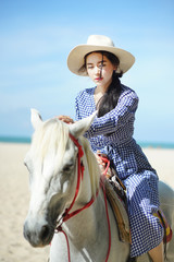 Beautiful woman riding a white horse at the beach