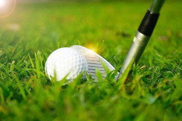 Blurred golf ball and golf club in beautiful golf course at sunset background.