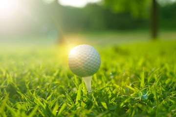 Blurred golf ball on tee in beautiful golf course at sunset background.