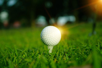 Blurred golf ball on tee in beautiful golf course at sunset background.