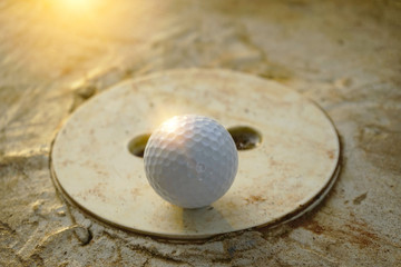 Blurred golf ball is on barrier in golf course at sunset background.