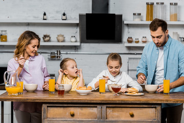 happy family eating porridge for breakfast in kitchen