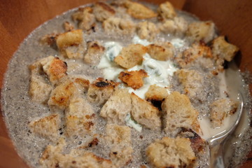 Homemade portobello mushroom soup in a wooden bowl with cream and croutons.