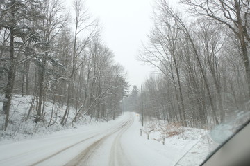 Driving on a road in snowy weather conditions. Lots of nature.