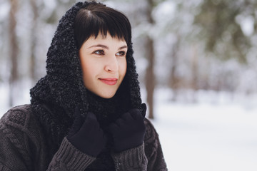 Young beautiful brunette girl in a sweater in the winter snowy forest