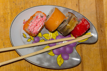 Sushi rolls with salmon, eel, cream cheese Philadelphia, caviar tobica and food sticks on the wooden background