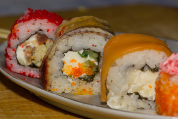 Sushi rolls with salmon, eel, cream cheese Philadelphia, caviar tobica on the plate. Wooden plank