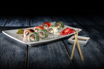 Fototapeta na wymiar Japanese cuisine. Sushi set on a wooden table over dark background