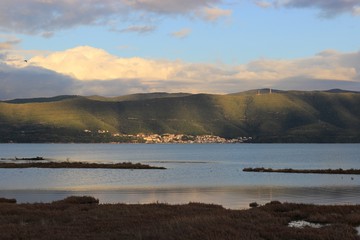 Background view of Menidi village in Aitoloakarnania at the shore of Ambracian (Amvrakikos) gulf green hills mountains shadows of the clouds from the Koprena lighthouse in Greece