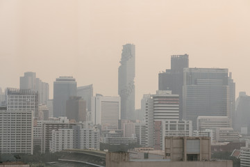 Air pollution effect made low visibility cityscape with haze and fog from dust in the air during sunset in Bangkok, Thailand. Image contain noise and grain.