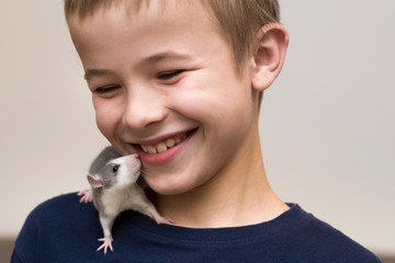 Portrait of happy smiling funny cute handsome child boy with white pet mouse hamster on shoulder on...