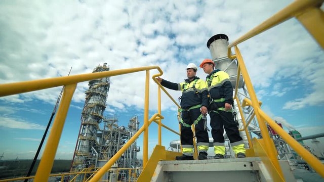 Male co-workers standing on tower and discussing industrial safety