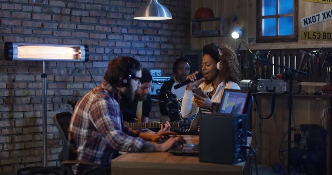 Musicians make audio very emotional music at home in the garage. They jump to the rhythm of the song