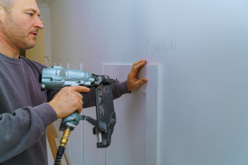 Wall moulding trim air gauge finish nailer man nailed custom house building contractor carpenter using nail gun