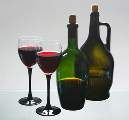 Two glasses of red wine and bottles