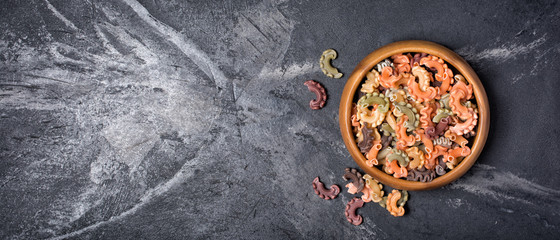 Fototapeta na wymiar Italian raw vegetarian color pasta on black marble background